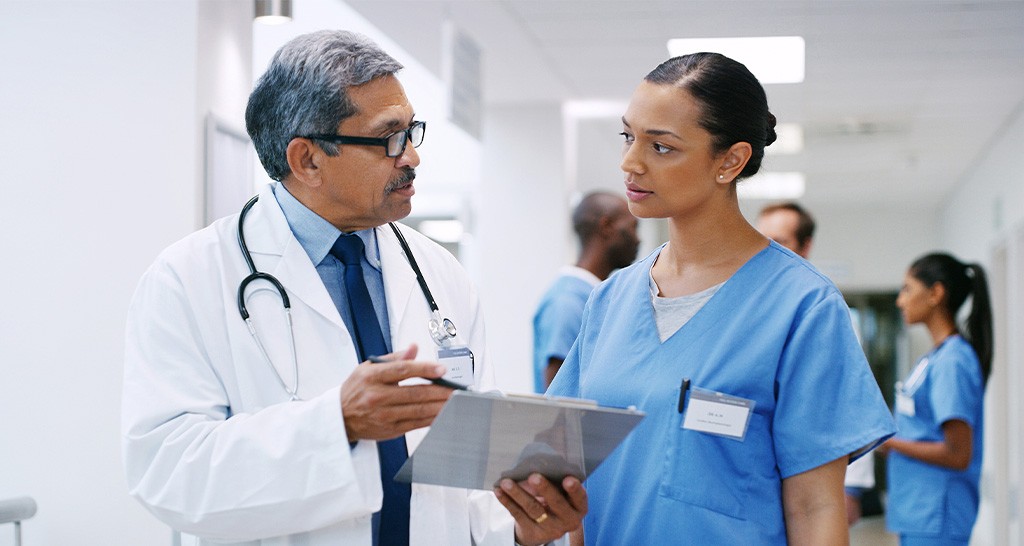 Two doctors have a conversation in a hospital hallway