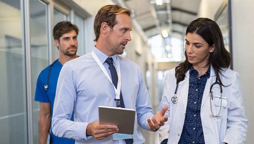 A doctor speaks with a business professional in a clinic lobby