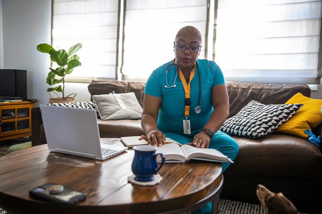 A doctor uses a laptop computer on the couch in her office
