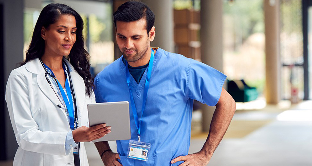 A doctor reviews data on a tablet computer with a nurse