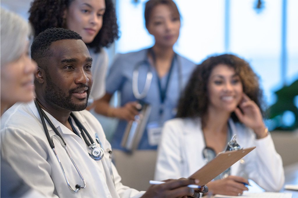 A team of doctors and nurses have a discussion in a conference room