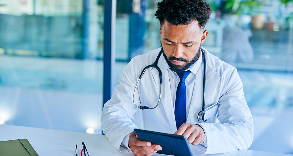 A doctor in white lab coat uses a tablet