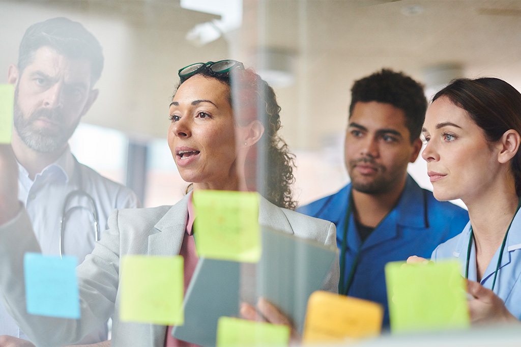 A consultant goes through a demonstration with medical professionals using sticky notes