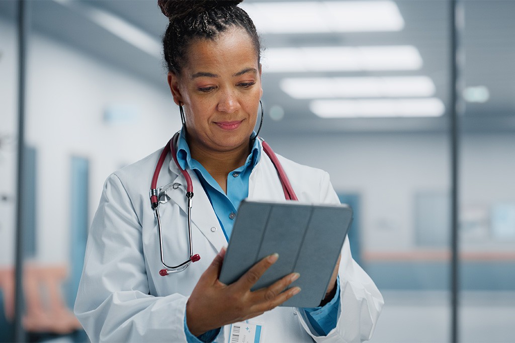 A doctor in white lab coat takes notes on a tablet