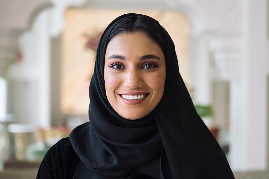 A woman in hijab smiles at the camera