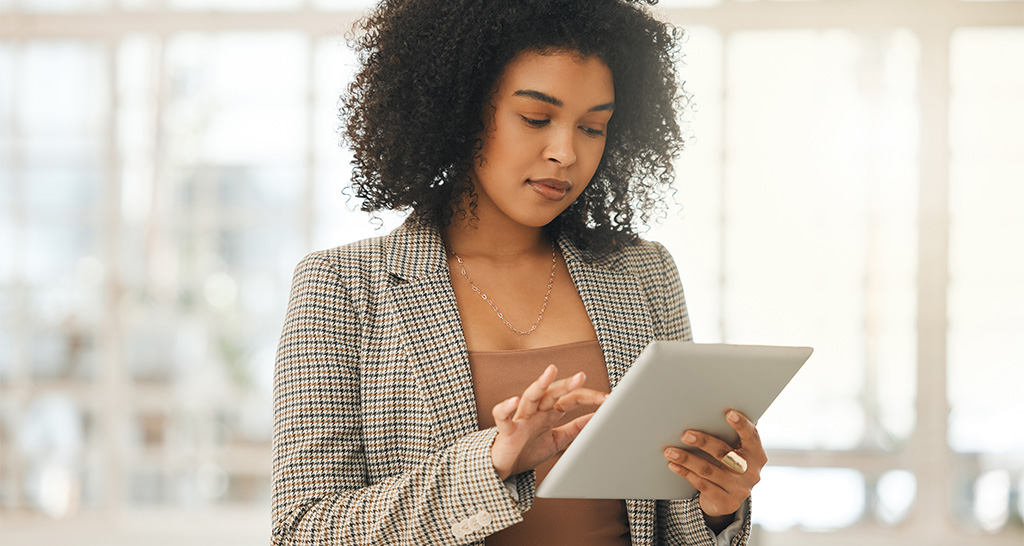 A woman in professional wear uses a tablet