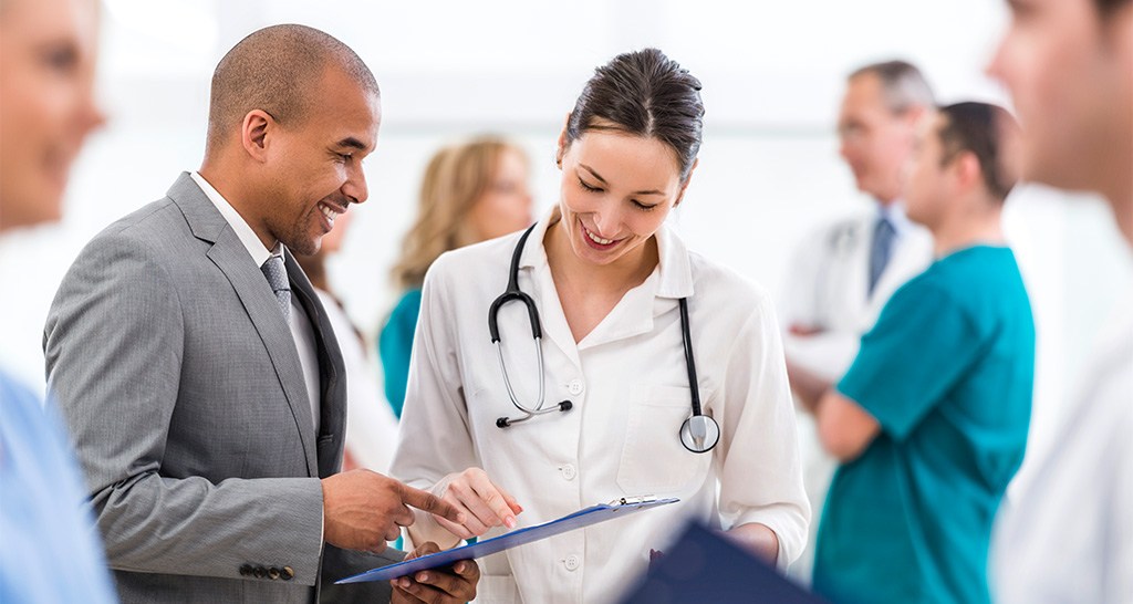 A man in a suit speaks with a doctor in a white lab coat