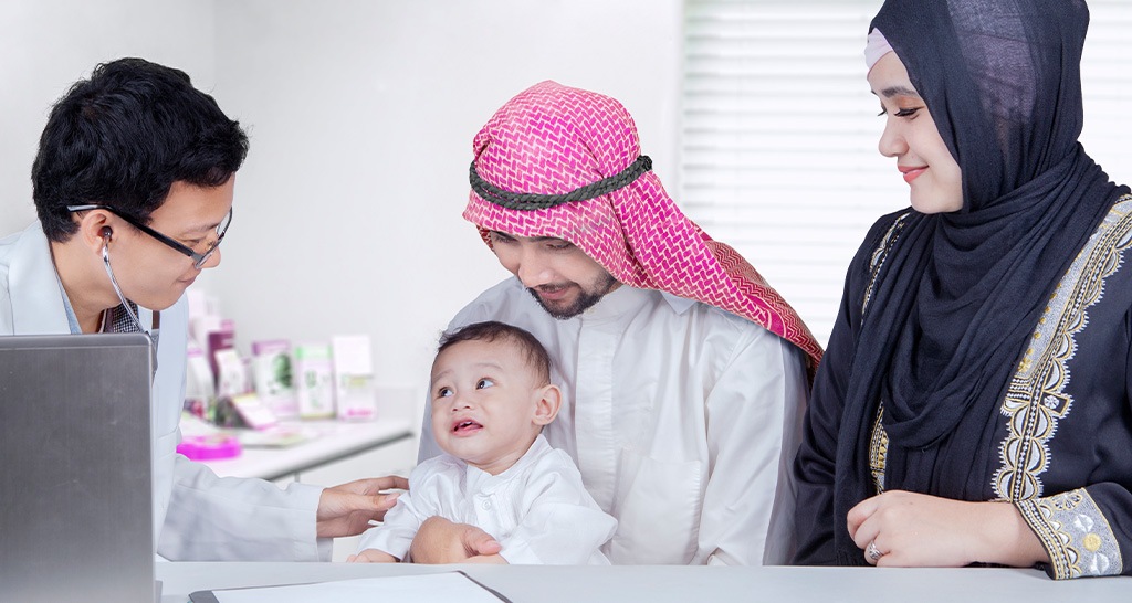 A doctor uses a stethoscope on a toddler accompanied by his parents